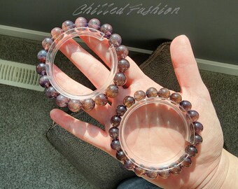 May include: Two bracelets with translucent, round, purple-brown beads. The bracelets are held in place by clear, circular holders. The bracelets are on a light skin tone background. The text "Chilled Fashion" is in the upper right corner.