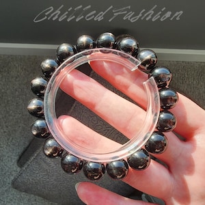 May include: A black beaded bracelet with a clear plastic ring. The bracelet is made of round, polished black beads. The text "Chilled Fashion" is written in cursive at the top of the image.