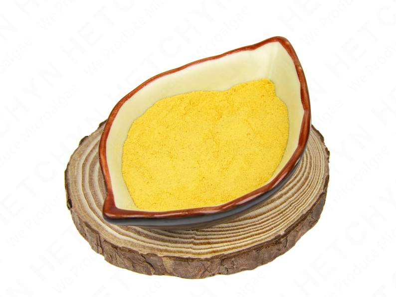 May include: A leaf-shaped ceramic bowl filled with yellow powder, resting on a round wooden slice. The bowl has a cream-colored interior with a brown rim. The wooden slice displays a natural wood grain.
