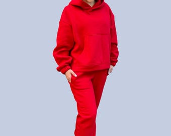 May include: A red hooded sweatshirt and matching sweatpants set. The sweatshirt has a kangaroo pocket and the sweatpants have a drawstring waist.