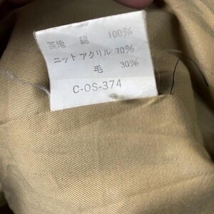May include: Close-up of a tan fabric with a white tag. The tag has Japanese text indicating the fabric composition: 100% cotton, 70% knit acrylic, and 30% wool. The tag also includes the code C-OS-374.