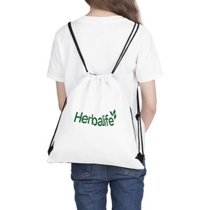 Op de afbeelding: Witte trekkoordtas met zwarte trekkoorden en het Herbalife-logo in groen.