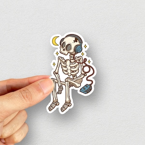 May include: A cartoon skeleton wearing headphones and sitting with a cassette player. The skeleton is white with black outlines and the headphones are blue. The cassette player is blue and white.