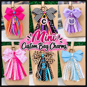 May include: Six custom bag charms featuring large fabric bows in various colors and patterns, including hot pink, black and white stripes, purple, light pink, leopard print, and light blue, with dangling ribbons and personalized charms.