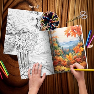 May include: A person coloring in a coloring book with a yellow pencil. The coloring book has two pages open, one with a black and white drawing of a house and trees by a lake, and the other with a colored drawing of a forest with fall foliage.