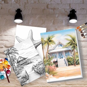 Op de afbeelding: Twee lege doeken met een strandhuis- en een zeesterontwerp. De doeken leunen tegen een bakstenen muur met kwasten en een palet in de voorgrond.