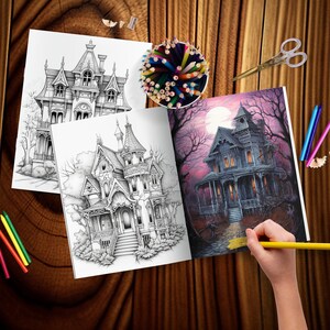 May include: An open coloring book with two black and white illustrations of a Victorian style house and a colored illustration of a spooky house with a full moon in the background. The book is on a wooden table with colored pencils and a pencil sharpener.
