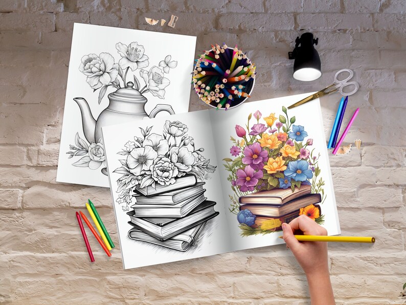 May include: An open adult coloring book with a floral design is being colored with a yellow pencil. A black and white floral design coloring book and a pencil holder with colored pencils are also visible. Scissors and crayons are on the table.