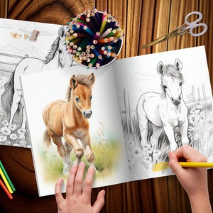 K&ouml;nnte beinhalten: Ein ge&ouml;ffnetes Malbuch mit zwei Seiten, auf denen jeweils eine Schwarzwei&szlig;illustration eines Pferdes zu sehen ist. Die linke Seite zeigt ein Pferd, das auf einem Feld steht, w&auml;hrend die rechte Seite ein Pferd zeigt, das rennt. Eine Hand h&auml;lt einen gelben Bleistift &uuml;ber die rechte Seite, bereit zum Ausmalen.