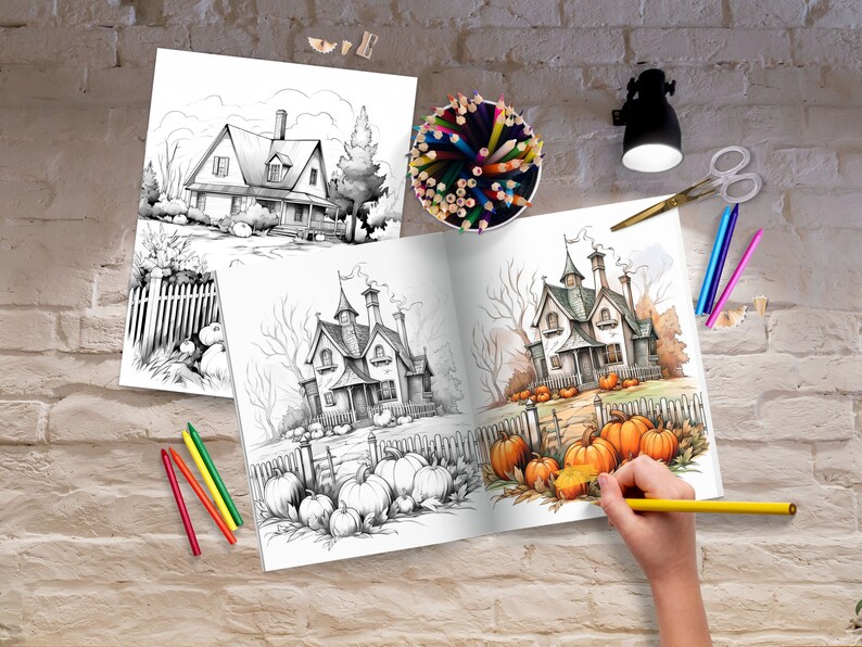 May include: An open coloring book with a black and white illustration of a house with a fence and pumpkins. The right page of the book is partially colored with orange pumpkins and a brown path leading to the house.