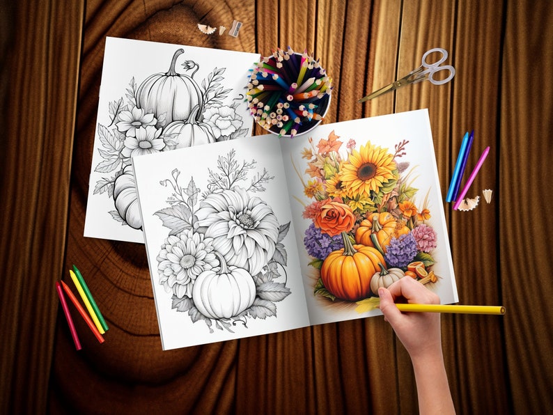 May include: An open coloring book with two pages showing black and white illustrations of pumpkins and flowers. The left page shows a group of pumpkins with leaves and flowers. The right page shows a bouquet of sunflowers, roses, and other flowers with pumpkins at the bottom. A hand is holding a yellow colored pencil over the open book.