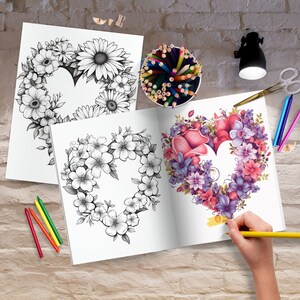 K&ouml;nnte beinhalten: Ein offenes Malbuch mit zwei Seiten, die ein herzf&ouml;rmiges Blumenmuster zeigen. Eine Seite ist mit rosa, lila und roten Blumen gef&auml;rbt, w&auml;hrend die andere Seite schwarzwei&szlig; ist. Eine Hand h&auml;lt einen gelben Bleistift und f&auml;rbt die Seite.