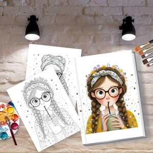 May include: Illustration of a girl with glasses and braids, drinking from a glass, surrounded by coloring book pages and art supplies. The girl wears a floral headband and a yellow sweater. A watercolor palette and paintbrushes are also visible.