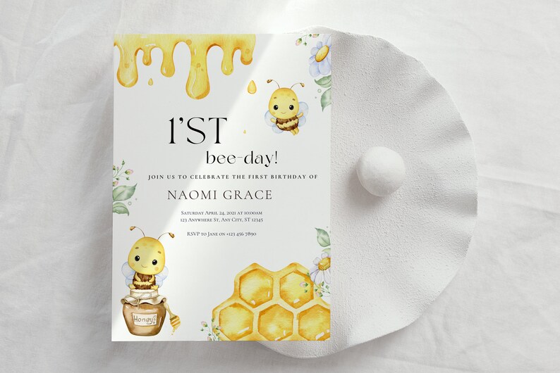 May include: A white invitation card with a yellow honeycomb design and a cartoon bee illustration. The text on the card reads "1'ST bee-day!" and "Join us to celebrate the first birthday of Naomi Grace".
