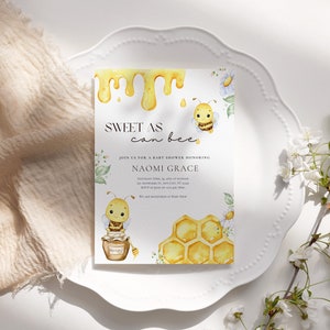 May include: A baby shower invitation with a bee theme. The invitation is white with yellow and black bees, honeycombs, and dripping honey. The text on the invitation reads "Sweet as can bee" and "Join us for a baby shower honoring Naomi Grace".