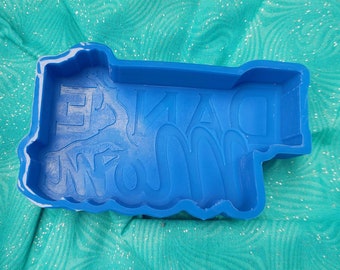 May include: Blue silicone mold for making a cake or other dessert. The mold is shaped like the words "Grandma's Famous".