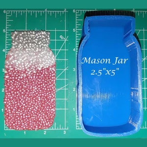 May include: Blue silicone mold shaped like a mason jar. The mold is 2.5 inches wide and 5 inches tall. The mold is on a green cutting mat.