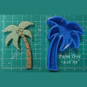 Puede incluir: Molde de silicona azul en forma de palmera, que mide aproximadamente 8,25 cm por 12,7 cm. El molde está sobre una estera de corte verde con marcas en pulgadas.