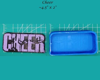 May include: A rectangular mold and a finished product. The finished product is a purple and black rectangle with the word "Cheer" and cheerleading figures. The mold is blue. The finished product is approximately 4.5 inches by 2 inches.