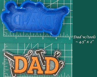 Puede incluir: Molde de plástico azul con la palabra "DAD" y diseños de herramientas. Debajo, un producto terminado con la palabra "DAD" en naranja, contorneada en blanco, y herramientas. El producto terminado mide aproximadamente 11,4 cm por 5,1 cm.