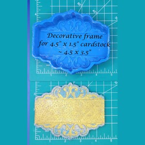 May include: Blue silicone mold for making decorative frames for 4.5 inch by 1.5 inch cardstock. The mold is shown on a green cutting mat with a ruler. The mold is 4.5 inches by 3.5 inches.