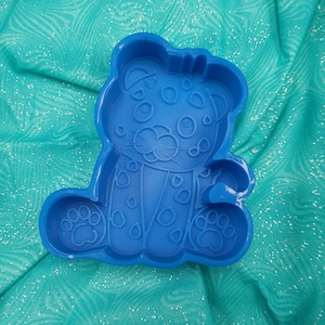 Könnte beinhalten: Blaue Plastikform in Form eines Leoparden mit gepunktetem Muster. Die Form hat ein erhabenes Design des Leopardenkopfes und der Pfoten.