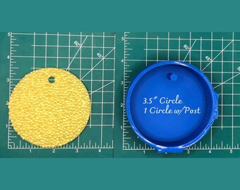 Op de afbeelding: Een blauwe siliconen mal voor het maken van een cirkel van 8,9 cm met een pen. De mal ligt op een groene snijmat met witte rasterlijnen. De tekst "3.5" Circle 1 Circle w/Post" is op de mal gedrukt.