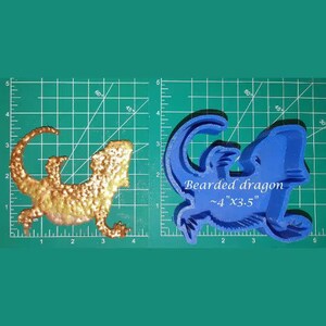 Könnte beinhalten: Eine blaue Silikonform eines Bartagamen, etwa 10 cm x 9 cm groß. Die Form befindet sich auf einem grünen Gitterhintergrund. Der Text "Bearded dragon ~4"x3.5"" ist auf die Form gedruckt.