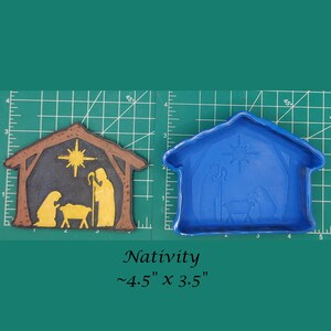 May include: A brown and blue plastic mold for making a nativity scene. The mold is approximately 4.5 inches by 3.5 inches. The mold is on a green cutting mat.