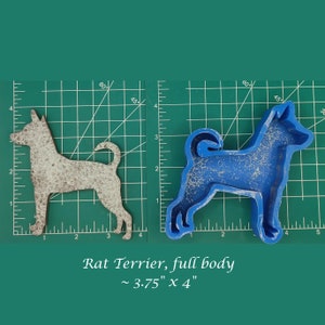 May include: A blue silicone mold of a Rat Terrier dog, approximately 3.75 inches by 4 inches, on a green cutting mat. The mold is next to a gray cutout of the same dog.