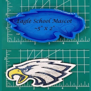 May include: Blue silicone mold of an eagle head, approximately 5 inches by 2 inches, with the text "Eagle School Mascot" on the mold. A separate image shows a gray and white eagle head graphic.