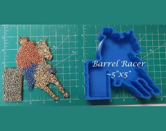 Puede incluir: Molde de plástico azul para hacer una figura de barril. El molde mide 5 pulgadas por 5 pulgadas y tiene las palabras "Barrel Racer" y "~5" x 5" escritas en él.