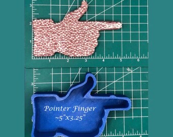 Puede incluir: Un molde de silicona azul con forma de dedo índice apuntando. El molde está sobre una estera de corte verde con marcas blancas. El molde está etiquetado "Pointer Finger ~5" x 3.25" "