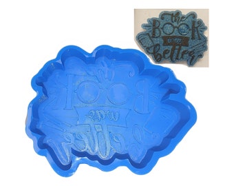 May include: Blue silicone mold for resin casting. The mold is shaped like a book with glasses and the text "The Book is always better".