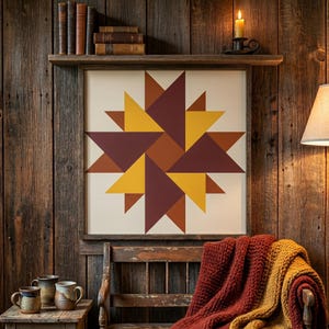 May include: A framed geometric wall art piece with a starburst design in shades of yellow, brown, and burgundy. The artwork is displayed on a rustic wooden wall, with a wooden shelf above holding books and a candle. A bench and throw blanket are in the foreground.