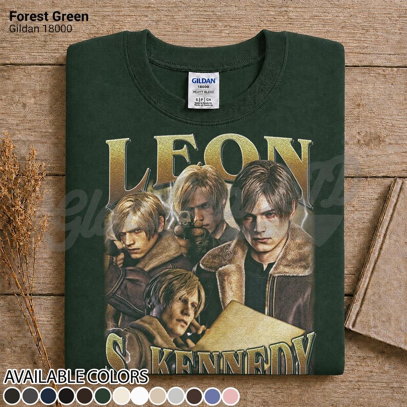 May include: A forest green Gildan 18000 sweatshirt featuring a graphic print of Leon Kennedy from Resident Evil. The design includes three depictions of the character in a brown jacket, with the name LEON KENNEDY in large gold lettering.
