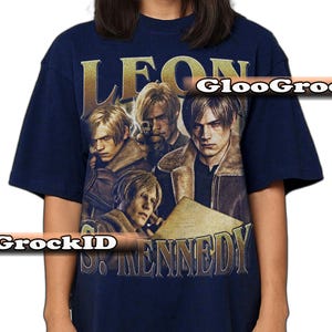 May include: A navy blue short-sleeve t-shirt featuring a graphic print of the character Leon S. Kennedy in multiple poses. The design includes the text "LEON" at the top and "S. KENNEDY" at the bottom in a metallic gold font, with a watermark overlay.