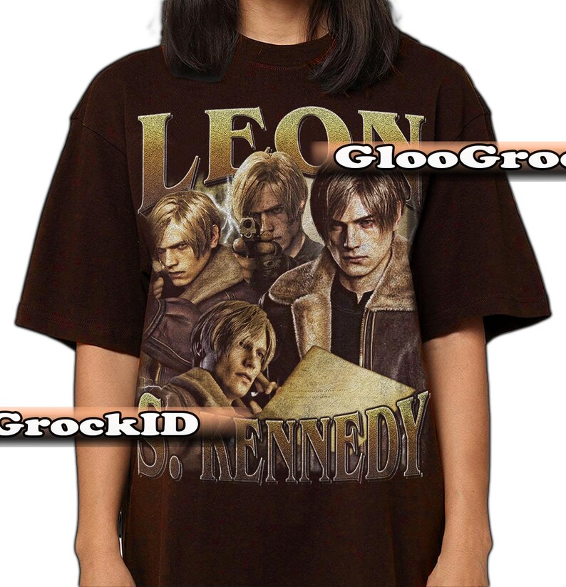 May include: A dark brown short-sleeve t-shirt featuring a graphic print of the character Leon S. Kennedy in various poses. The text LEON is printed in large gold letters at the top, and S. KENNEDY is printed in gold letters at the bottom of the graphic.