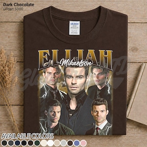 May include: Dark chocolate brown t-shirt with a graphic of Elijah Mikaelson. The design features multiple images of the character with gold lettering. The shirt is a Gildan 5000, available in various colours.