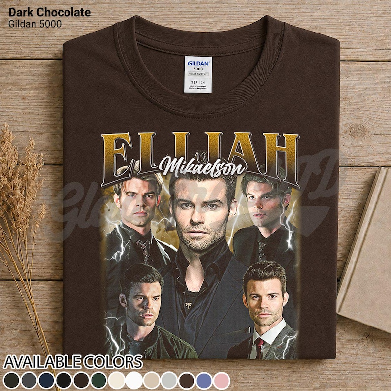 May include: Dark chocolate brown t-shirt with a graphic of Elijah Mikaelson. The design features multiple images of the character with gold lettering. The shirt is a Gildan 5000, available in various colours.