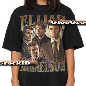 K&ouml;nnte beinhalten: Schwarzes T-Shirt mit einem Vintage-Design, das vier M&auml;nner und den Text "Elijah Mikaelson" in Gold zeigt. Die Grafik enth&auml;lt Portr&auml;ts der M&auml;nner in Anz&uuml;gen und Jacken.
