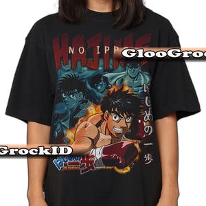 Op de afbeelding: Een zwart T-shirt met korte mouwen en een grafische print van de anime-serie Hajime no Ippo. Het ontwerp bevat meerdere personages, rode en blauwe tekst en Japanse karakters. Het centrale figuur draagt rode bokshandschoenen in een dynamische houding.
