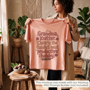 May include: A peach-colored t-shirt featuring the text "Grandma. Knitter. Clearly the family's most productive hobby." The design includes illustrations of yarn balls and knitting needles in a dark brown color, printed on the front of the shirt.