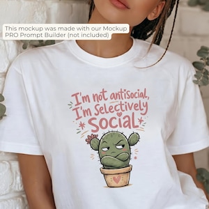May include: A white short-sleeved t-shirt featuring a graphic of a grumpy green cactus in a tan pot with arms crossed. The text above the cactus reads, "I'm not antisocial, I'm Selectively Social" in pink and brown lettering with small hearts.