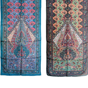 Puede incluir: Dos bufandas rectangulares con intrincados diseños de cachemira. Una bufanda es de color turquesa con patrones florales rosas, azules y blancos. La otra es gris oscuro con patrones florales naranjas, verdes y rosas. Ambas tienen un motivo central de cachemira.