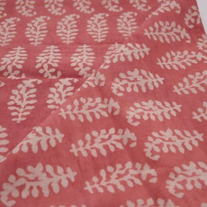 Puede incluir: Una tela rosa con un patr&oacute;n floral blanco. La tela tiene una textura sutil y un aspecto suave, ligeramente descolorido.