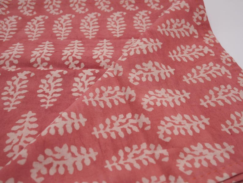 Puede incluir: Una tela rosa con un patr&oacute;n floral blanco. La tela tiene una textura sutil y un aspecto suave, ligeramente descolorido.