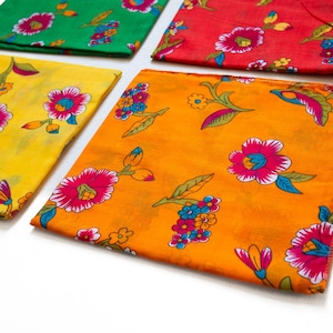Op de afbeelding: Vier kleurrijke bloemen zakdoeken. De zakdoeken zijn geel, oranje, groen en rood. Elke zakdoek heeft een herhalend patroon van roze en witte bloemen met blauwe accenten en groene bladeren.