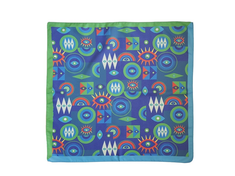 May include: A blue silk scarf with a repeating pattern of colorful eyes, circles, and diamonds. The scarf has a green border and a blue trim.