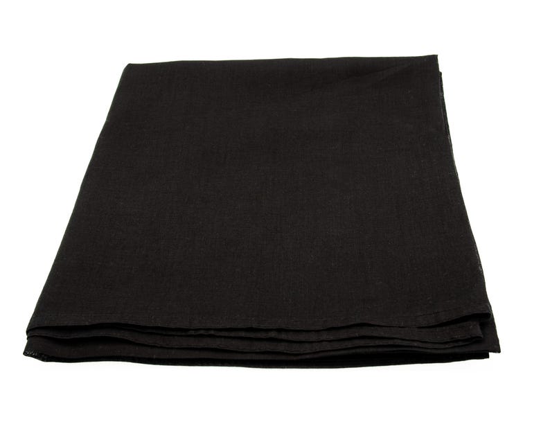 May include: A folded, black linen tablecloth. The fabric appears to be a solid color with a slightly textured surface. The tablecloth is neatly folded, with visible layers.